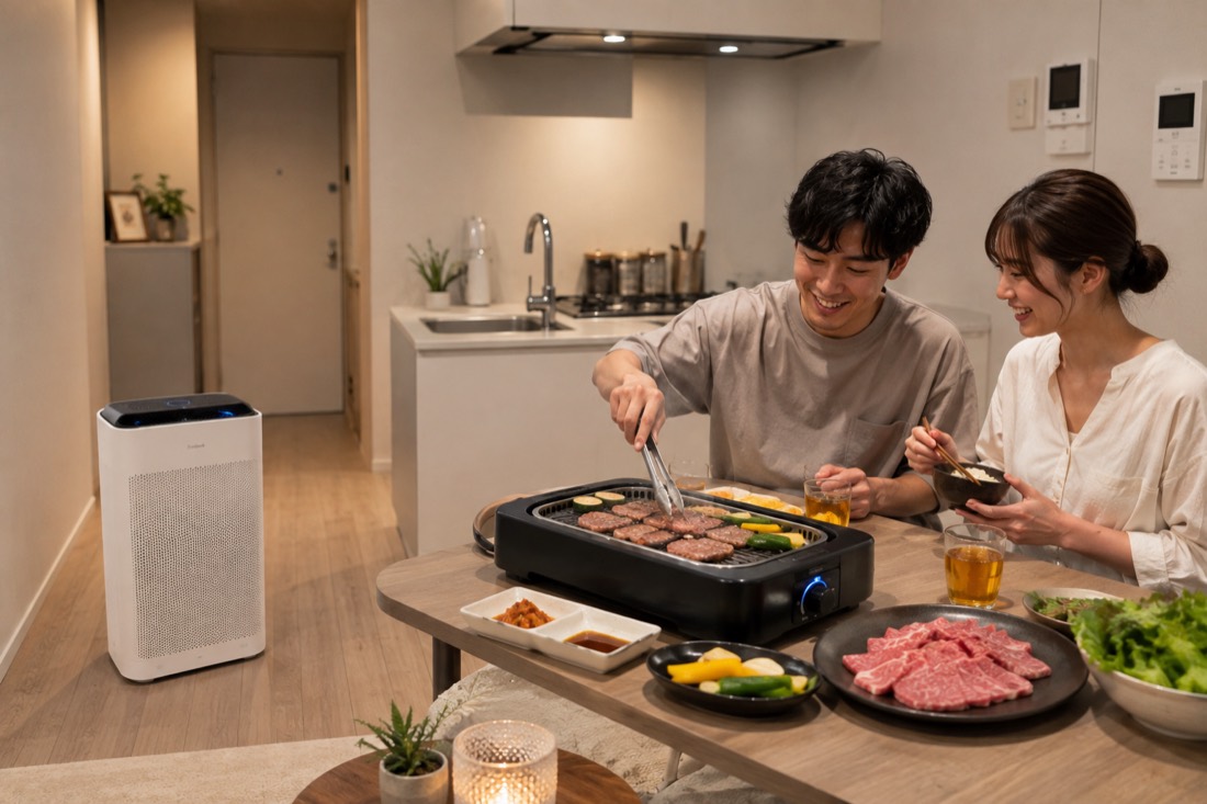 賃貸マンションのリビングで、空気清浄機を置き無煙ロースターで焼肉を楽しむカップル