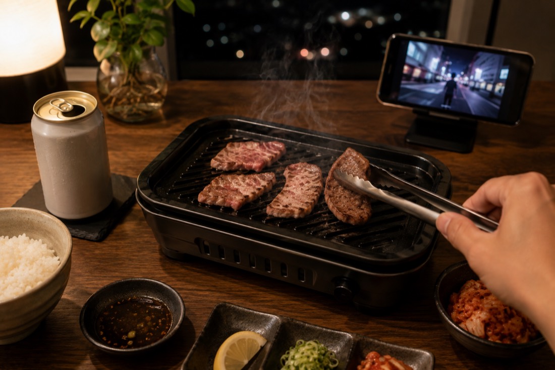 夜の食卓で卓上グリルを使って一人焼肉。ビールとごはん、スマホで動画を見ながらのリラックスした時間