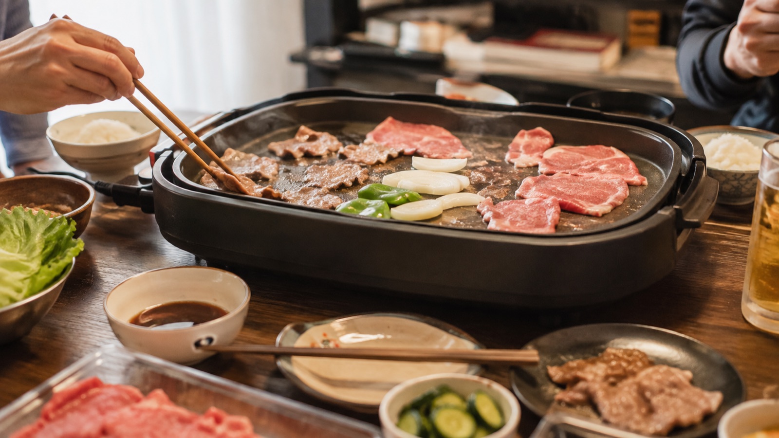 家庭の電気ホットプレートで薄切りの焼肉を焼いている、ごく普通のおうち焼肉のシーン