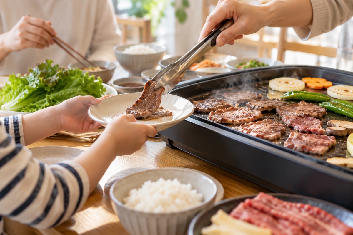 ホットプレート焼肉で子どもの取り皿に肉を取り分ける様子