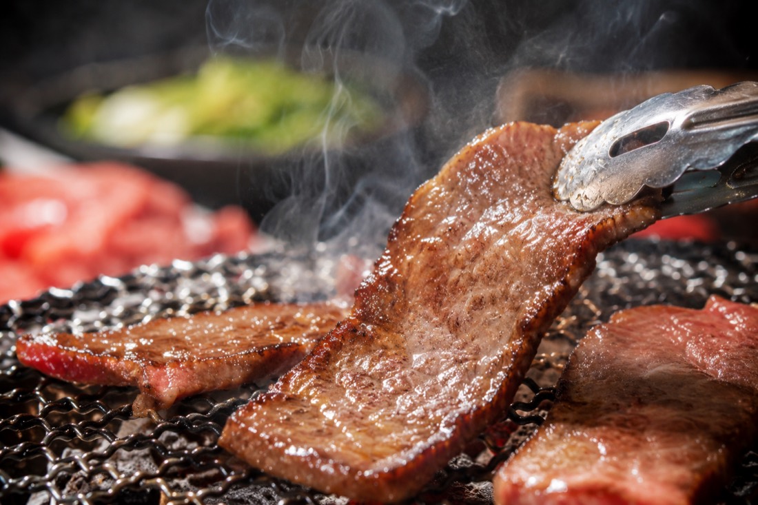 卓上のグリルで焼く豚バラ肉（サムギョプサル）とサンチュ・キムチが並んだ韓国焼肉の食卓